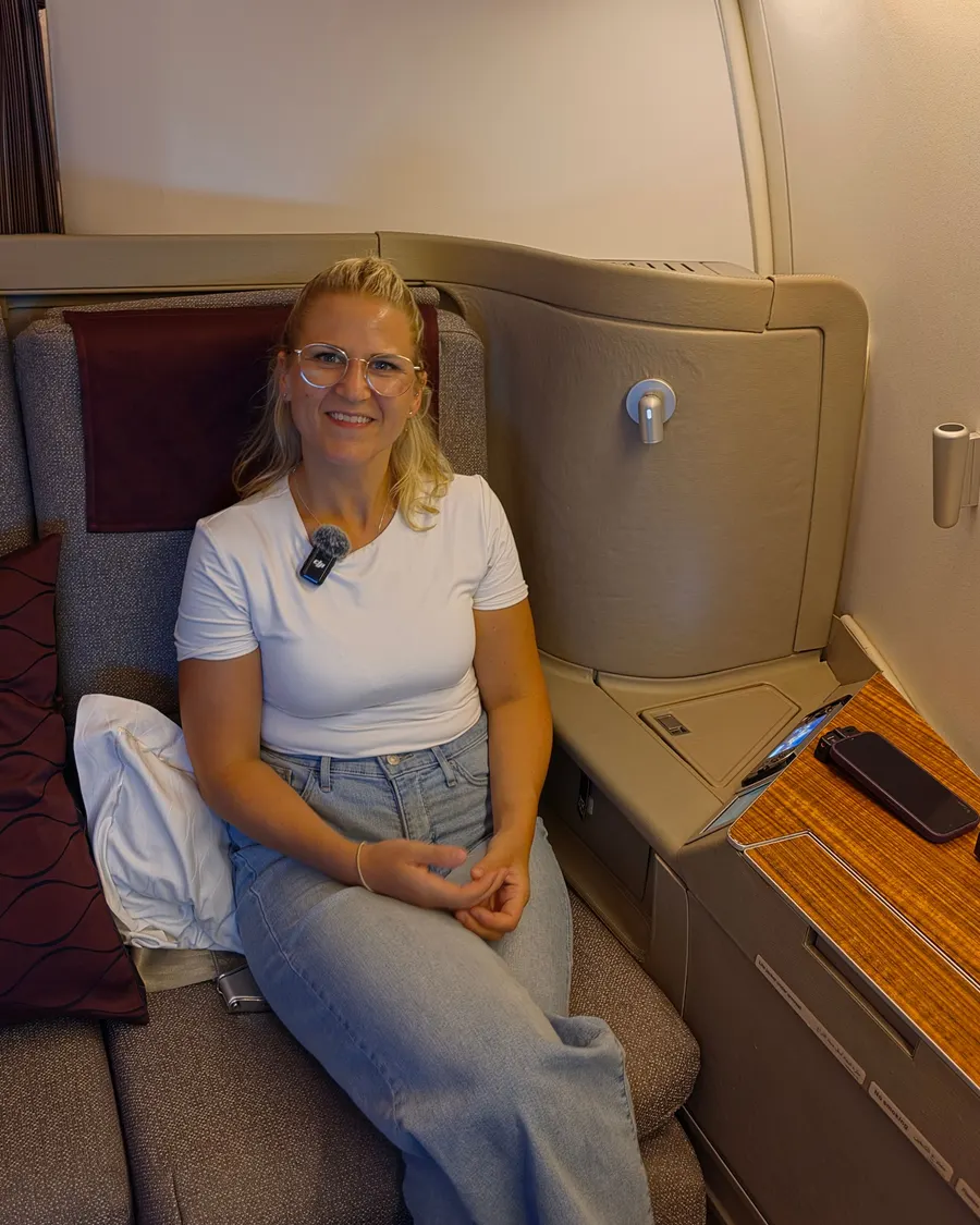 Janine sitzt lächelnd in ihrer Kabine im Flugzeug