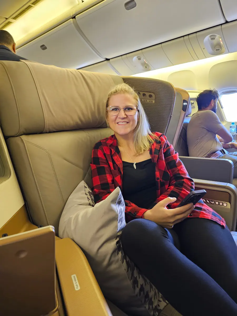 Janine sitzt lächelnd in ihrem Business Class Sitz bei Singapore Airlines.