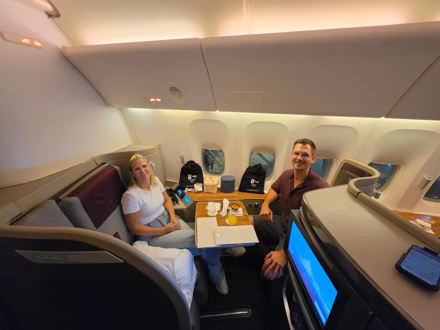 Janine und Timo sitzen in ihrer Kabine im Flugzeug und lächeln in die Kamera.