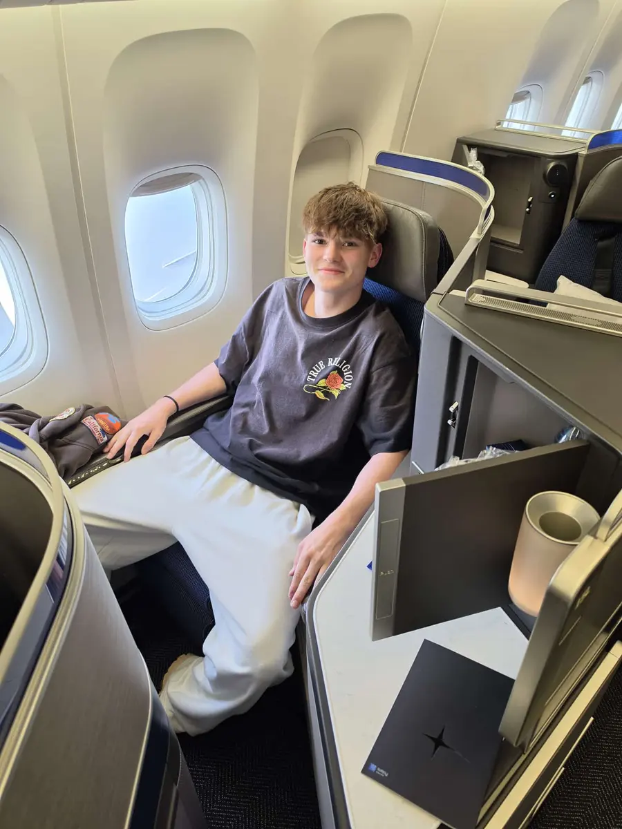 Unser Sohn sitzt in einem Business-Class-Sitz am Fenster.