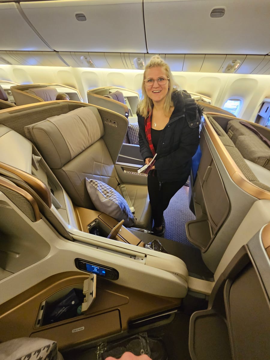 Janine steigt in die Business Class von Singapore Airlines ein und hält die Bordkarte in der Hand.